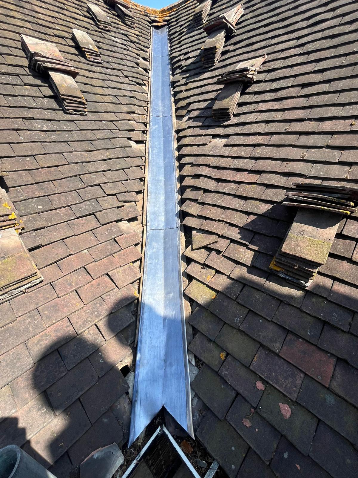 New lead valley installed between two pitched slate roofs