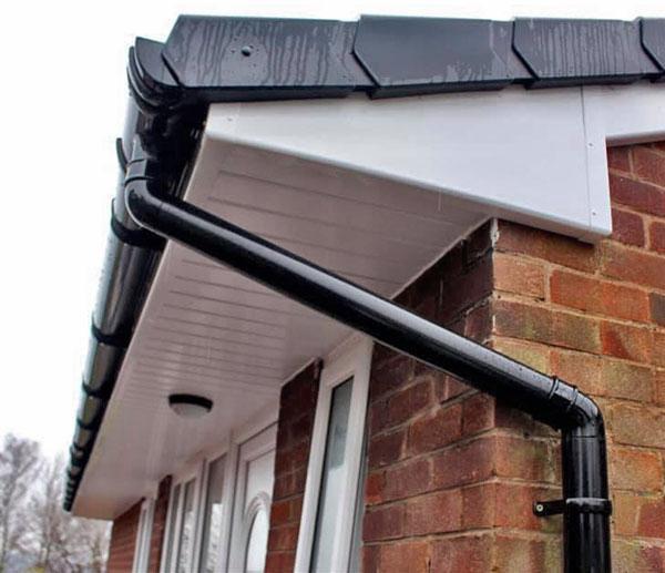 New black round-line guttering and downpipe on brick house